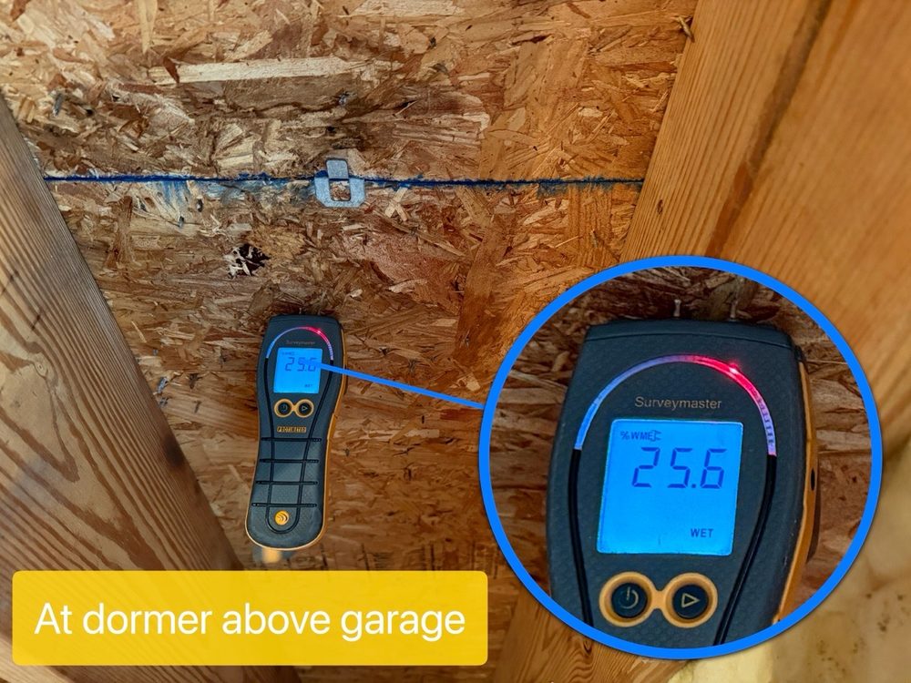 Moisture meter reading wet at roof sheathing above a garage dormer