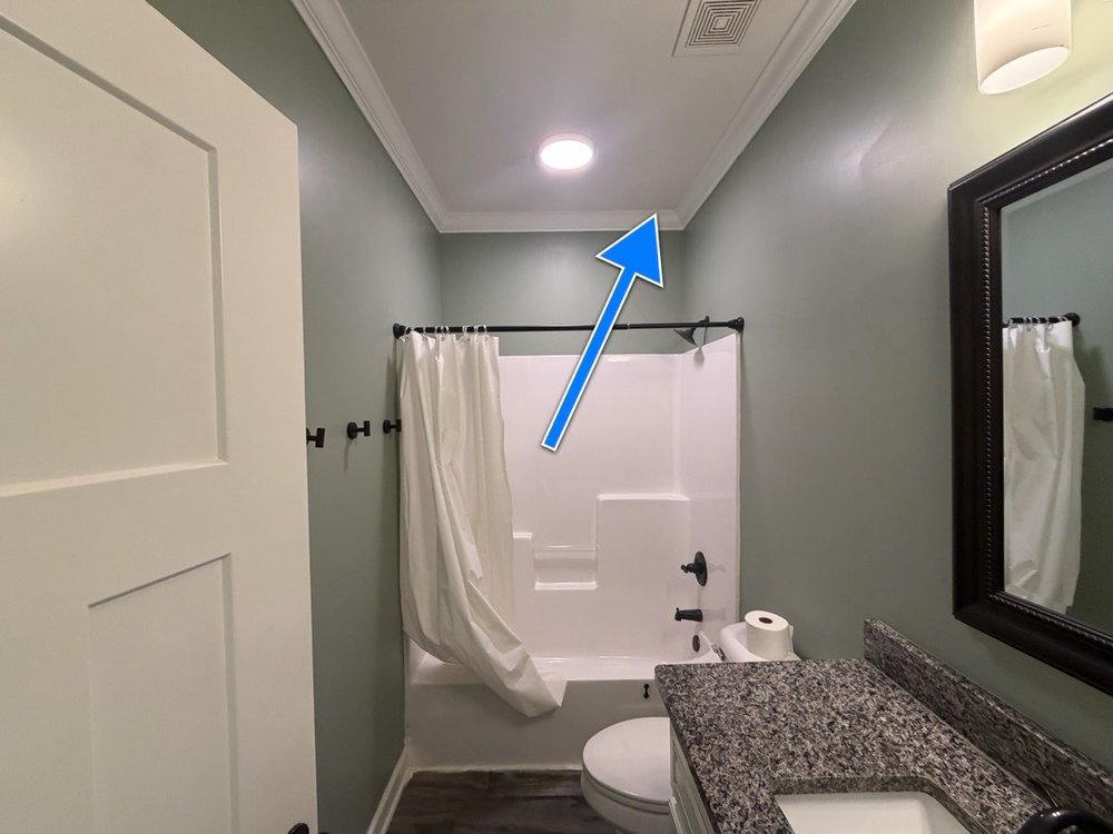 Bathroom ceiling corner near a shower, no visible signs of moisture