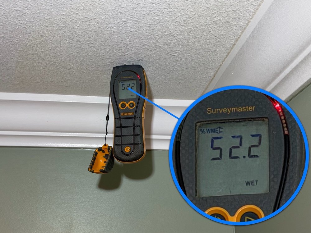 Moisture meter reading 52.2 percent wet on a ceiling near crown molding