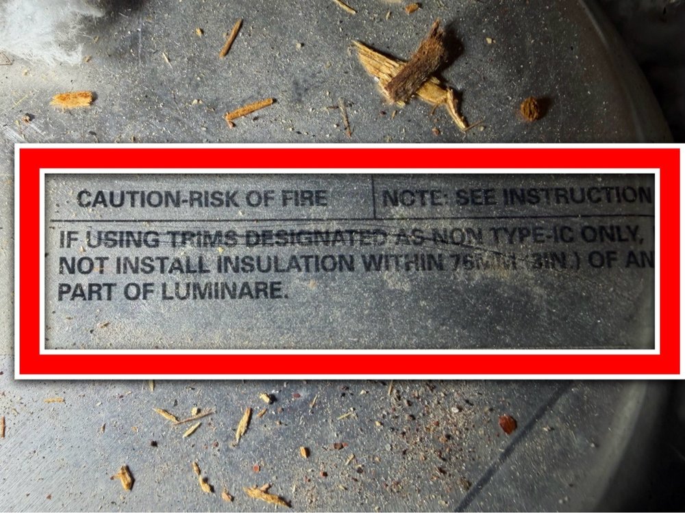 Warning label on a light fixture stating risk of fire if insulation is installed too close
