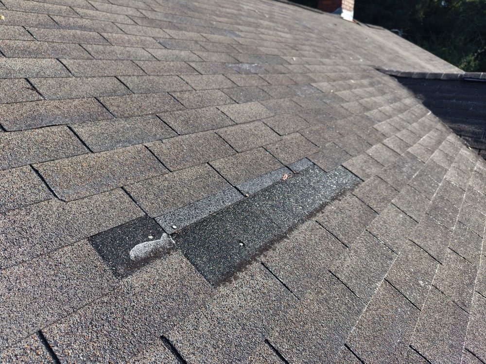 Close-up of a patched roof section with loose shingles nearby