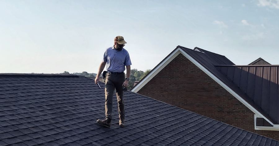 Inspector walking a shingle roof during inspection